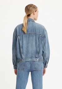 Jeansjacka med lös passform, ljusblå nyans och knäppning framtill. Har en klassisk krage och stickade detaljer på baksidan.