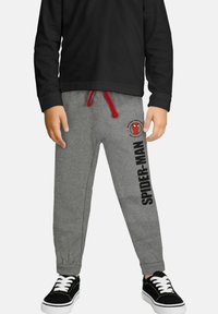 Gray sweatpants with red drawstring; features a Spider-Man logo and printed text on the left leg; paired with black sneakers.