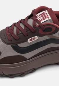 Bordogul og grå sneakers med teksturert stoff, svart logostrek, høy toppdesign, flate snører og gummiert såle.