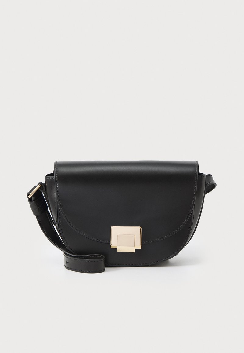 Sac en cuir noir à bandoulière avec un rabat arrondi, doté d'un fermoir en métal doré et d'une bandoulière plate. Texture lisse avec des coutures visibles.