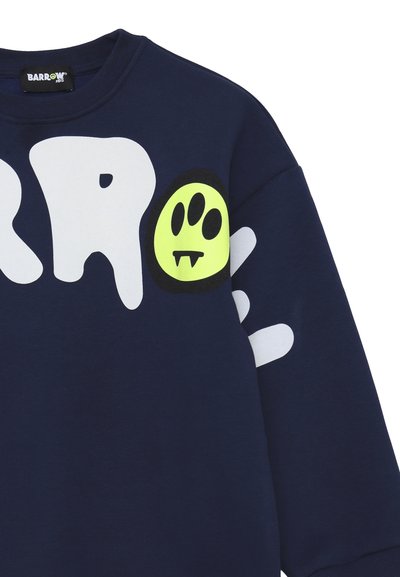 Il felpa blu navy presenta grandi lettere bianche in stile graffiti e una grafica di fantasma giallo neon con contorni neri sul petto.