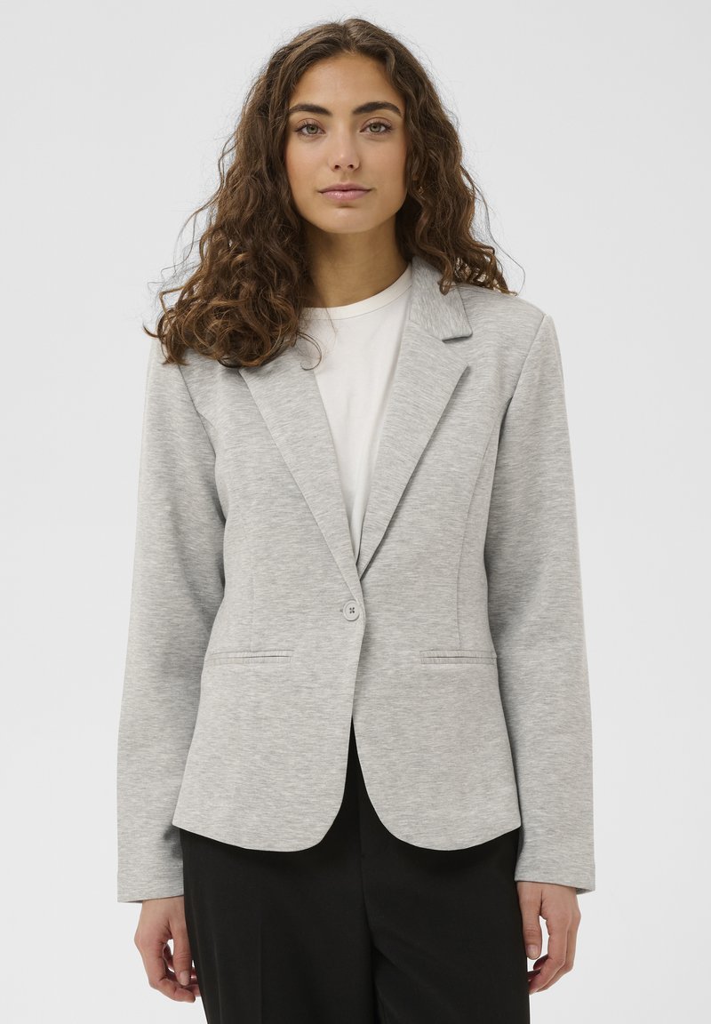 Blazer gris clair en tissu doux et texturé, doté d'un col à revers, d'une fermeture à un bouton et de poches latérales.