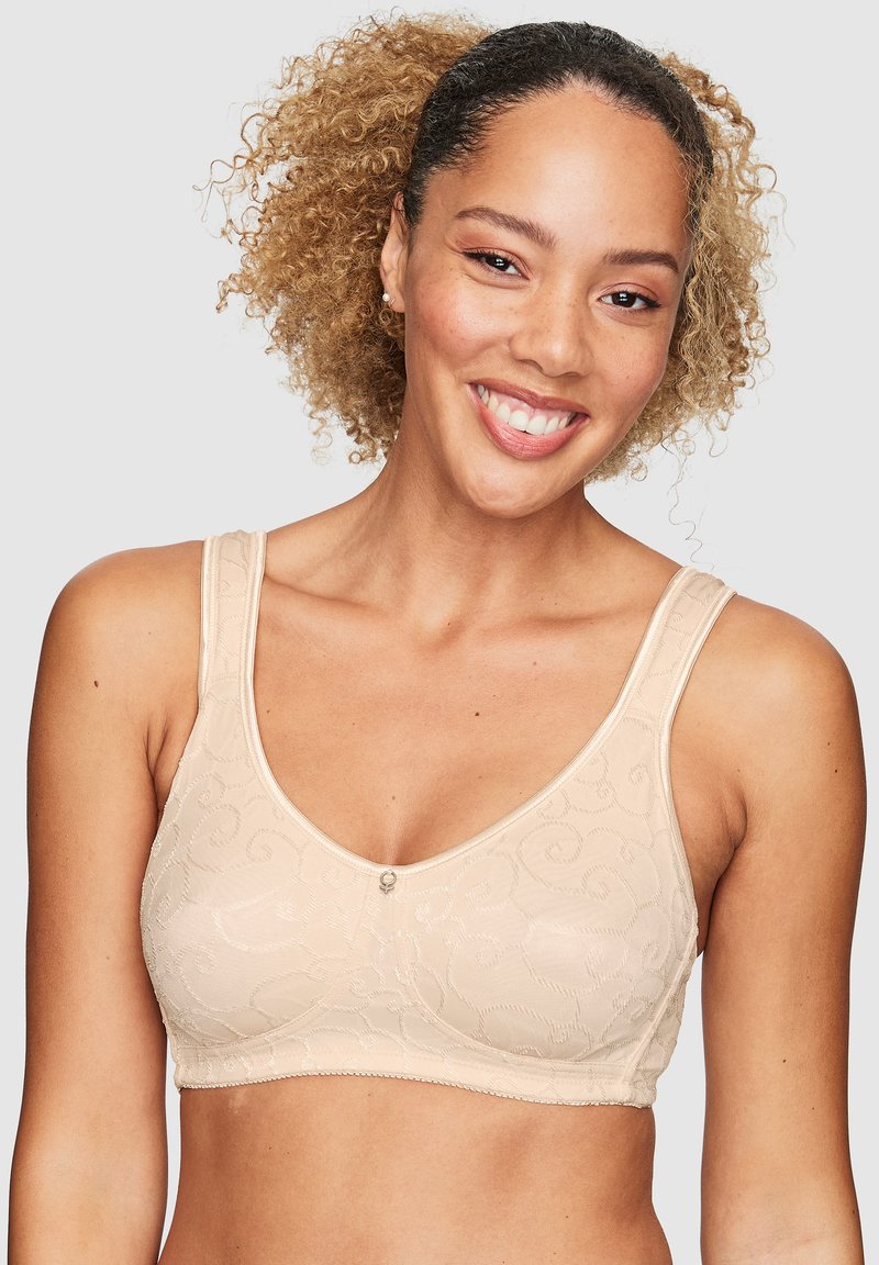 Beige spetsbh med blommönster, mjuk textur, breda band och en dekorativ knappdetalj i mitten.