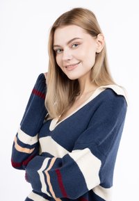 Pulover în dungi bleumarin și crem, cu guler în V și mâneci lungi, având o textură moale și dungi contrastante în culorile roșu și piersică.