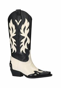 Botte de cowboy en cuir noir et blanc avec découpes en forme de flammes, bout pointu et talon empilé. Le dessus présente un motif décoratif aux couleurs contrastantes.