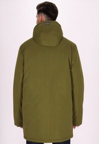 Giacca impermeabile verde con colletto alto e cappuccio attaccato, caratterizzata da una texture liscia e un taglio dritto, che arriva a metà coscia.