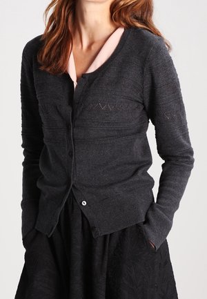 Charcoalgrijze button-up cardigan met een textuur gebreid patroon en geribde manchetten. Draag hem over een lichtroze overhemd met kraag.