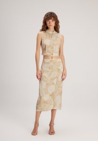 Blusa sin mangas cortada y falda midi a juego en un tejido floral beige con una textura suave, que cuenta con un cierre de botones y patrones sutiles.