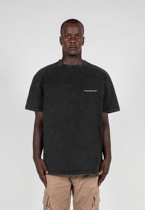 Black oversized T-shirt made of denim fabric with a crew neckline and short sleeves. Features a small white logo on the chest.