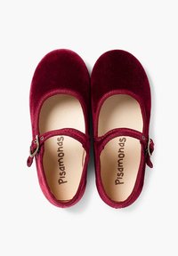 Zapatos Mary Jane de terciopelo burdeos con punta redondeada, hebilla metálica ajustable y suave forro interior que muestra el logo "Pisamonas".