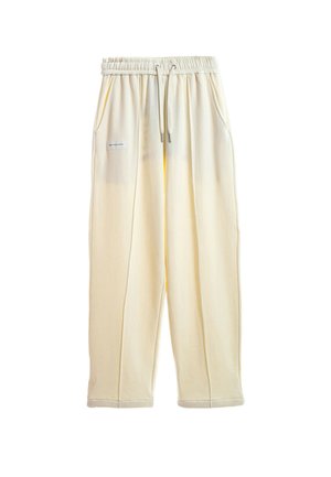 Pantalones casual de color crema con cintura elástica, cordones, bolsillos laterales y un pequeño parche rectangular en el muslo izquierdo.