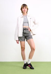 Hvit og stripete oversized skjorte, grå crop top, grå denimshorts, hvite sokker og svarte sko med rosa detaljer på et grønt gulv.