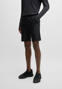 Shorts de sport noirs avec une coupe décontractée, fabriqués en tissu léger, dotés d'une taille élastique et de poches latérales.