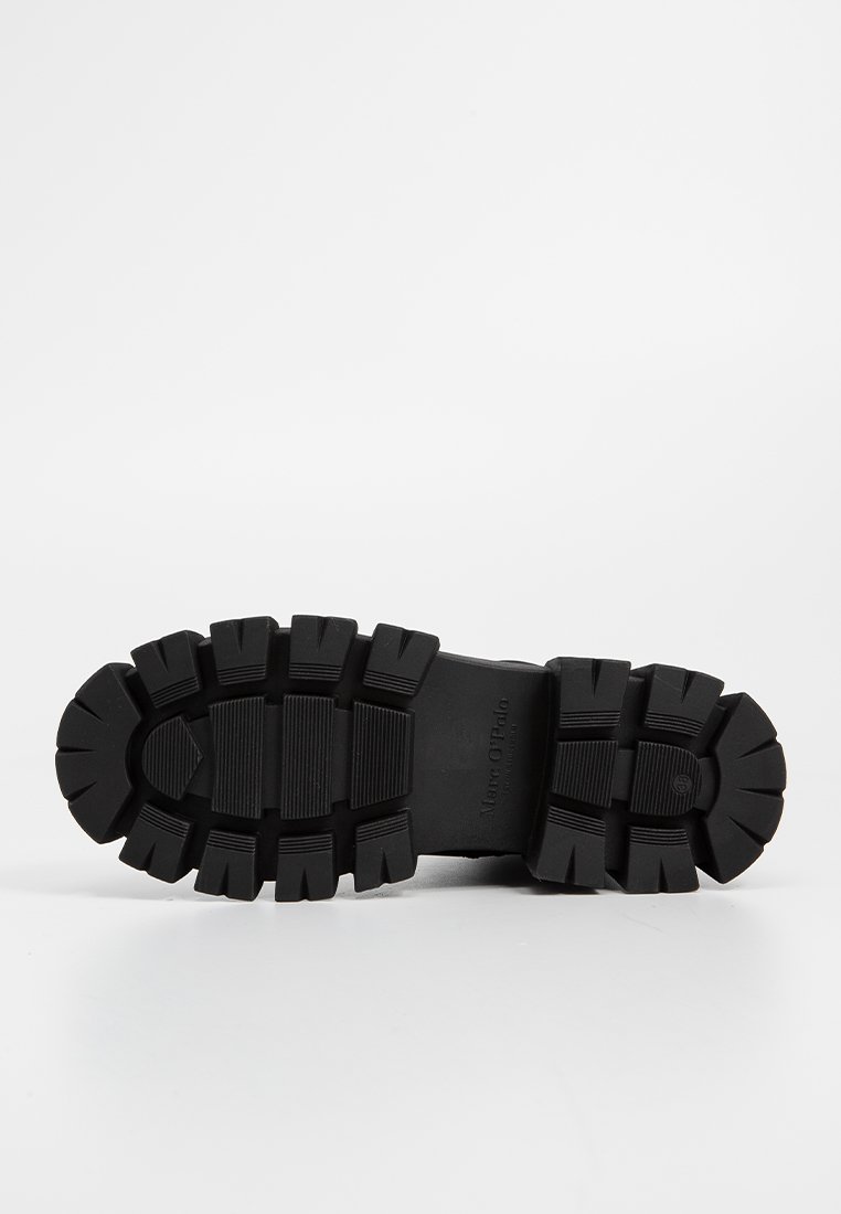 Suela de bota de goma negra con surcos profundos y ranuras para tracción, mostrando el nombre de la marca "Marc O'Polo" grabado en el medio.