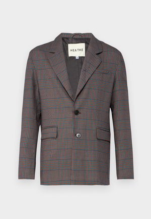 Geruite blazer in grijs, rood en blauw. Voorzien van een enkele knoopsluiting, reverskraag en twee voorzakken. Gemaakt van een op maat gemaakte stof.