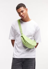 Borsa a tracolla in tessuto verde chiaro con una trama liscia, caratterizzata da una sola tracolla, forma arrotondata e un design arricciato sul fronte.