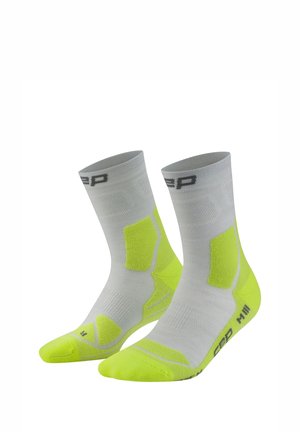 Pair of gray and neon yellow athletic socks with cushioned areas and brand logo on cuff and sole.