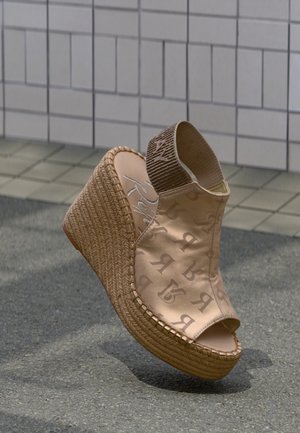 Sandale à talon compensé beige avec semelle plateforme tissée, bout ouvert et bride de cheville élastique ornée de motifs de lettres imprimées.