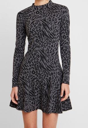 Vestido gris de manga larga con estampado animal negro y falda acampanada, llevado por una persona con las manos relajadas a los lados.