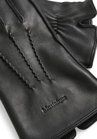Guanti in pelle nera con dettagli cuciti, caratterizzati da una texture liscia e un design con dita scoperte per un uso tattile. Accentuati da un branding sottile.