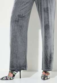 Graue Samtweite Hosen mit weicher Textur, kombiniert mit mehrfarbigen High Heels, die Ausschnittstreifen und eine spitze Zehe haben.
