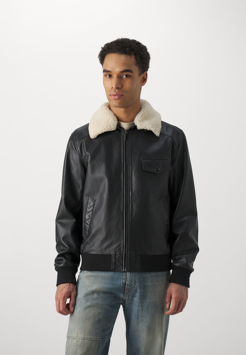 Black leather jacket with a cream faux shearling collar, front zip closure, and side pockets. Features ribbed cuffs and hem.