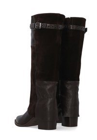 Vysoké boty s tmavě hnědým semišovým svrškem, koženými doplňky a detailním přezkou. Robustní podpatek a hladký povrch špičky.