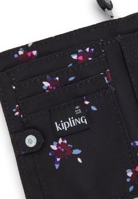 Kipling wallet in black fabric featuring a floral pattern. Includes multiple card slots and an RFID safe tag, secured with a snap button.