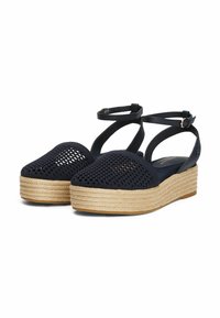 Sandalias de cuña de tela tejida azul marino con suela de esparto, que presentan correas en el tobillo y un patrón de punto texturizado.