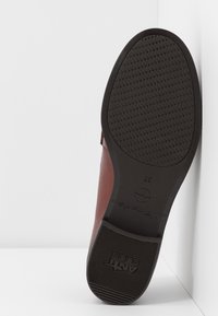 Semelle d'une chaussure marron montrant une bande de roulement en caoutchouc antidérapante avec les inscriptions "ANTI SLIDE" et la taille 37 sur fond blanc.