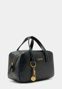 Sac à main en cuir noir texturé avec deux poignées courtes, garniture en or, fermeture éclair et détail charmé avec logo. Design rectangulaire compact.