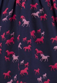 Navyfarbener Stoff mit einem wiederholten Muster von rennenden Pferden in Pink und glitzerndem Pink. Verschiedene Größen und Posen der Pferde über den Stoff verteilt.