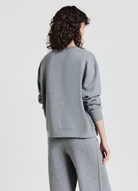 Felpa grigia in cotone misto con vestibilità rilassata, scollo rotondo, polsini e orlo a coste. La parte posteriore presenta una texture liscia e un design minimale.