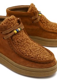 Bruine suède enkelboots met een textuur en pluizige bovenkant, vetersluiting met meerkleurige kraaltjes en een bruine rubberen zool.