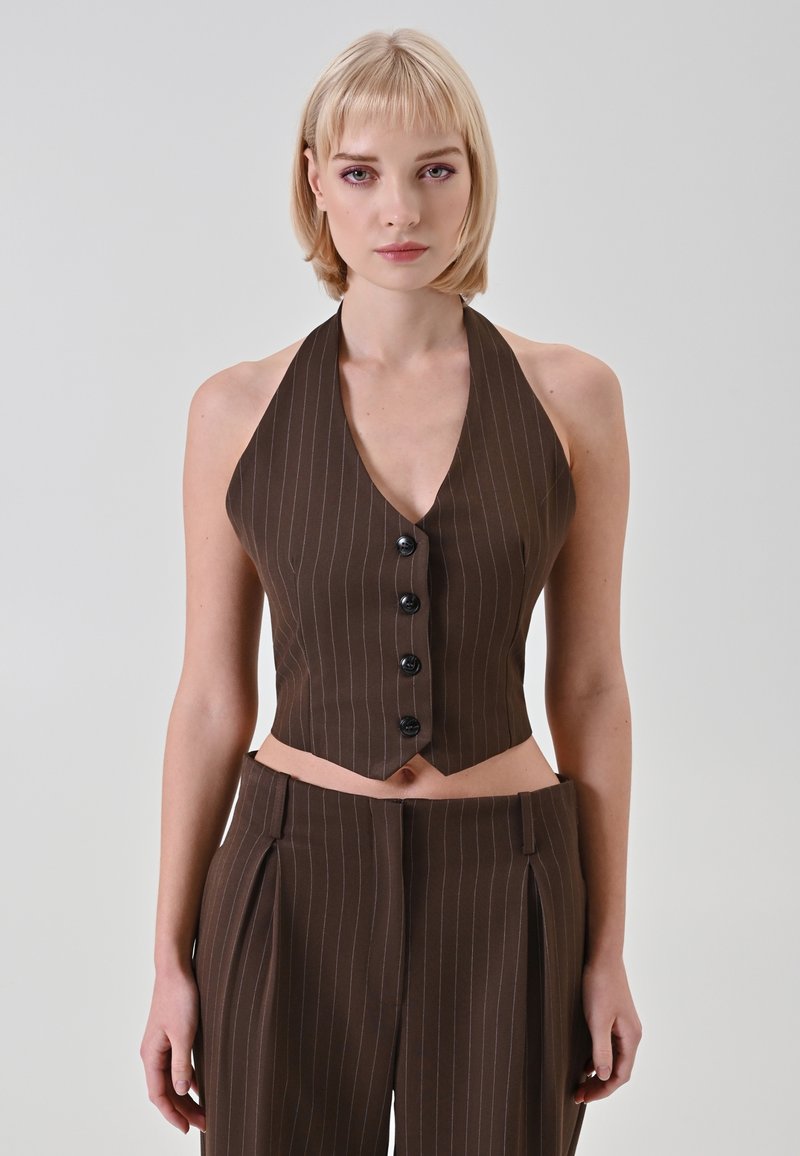 Top marrone a righe sottili con scollatura a V profonda e sei bottoni neri. Il design presenta una silhouette corta e una texture liscia.