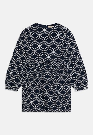 Mørkeblå kjole med hvitt geometrisk mønster, samlet midje, rund halslinje og lange ermer. Stoffet er teksturert bomull.