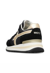 Sneaker nera con dettaglio a stella beige, suola bianca e beige, e branding "W6YZ" sul tallone, mostrata da un'angolazione laterale posteriore.
