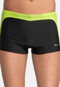 Schwarze Badeshorts mit einem neongelben Bund und seitlichen Akzenten. Hergestellt aus glattem Stoff, mit einem figurschmeichelnden Design und einem Logo auf dem Bein.