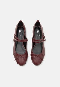 Ballerines en simili cuir bordeaux avec un bout rond, dotées de doubles brides de cheville et d'un détail en nœud à l'avant. Texture lisse et design épuré.