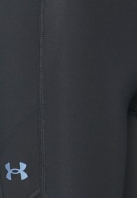 Leggings deportivos negros con una textura suave, que presentan un detalle del logo en azul y costuras planas para mayor durabilidad.