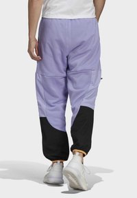 Lila och svarta cargobyxor med elastiska fållar och sidofickor, med en färgblockdesign och mjukt, texturerat tyg.