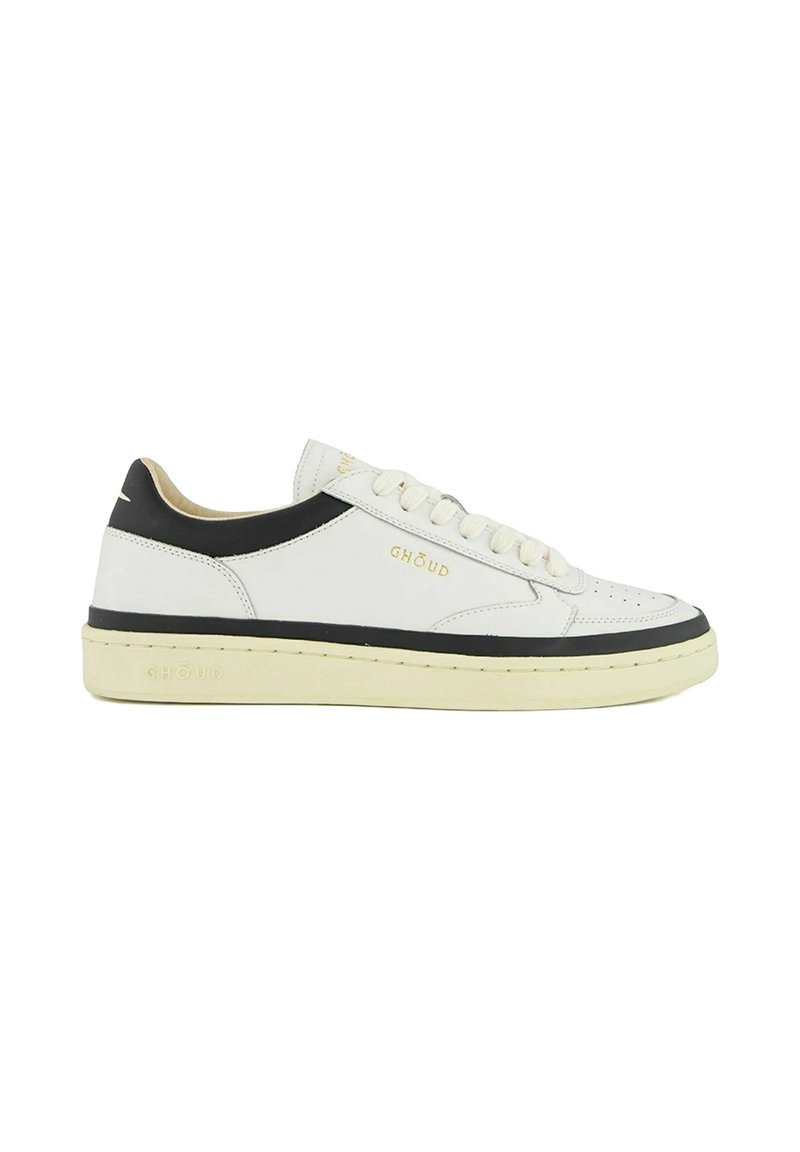 Sneaker bianca in pelle con dettagli neri, punta arrotondata, lacci piatti bianchi e suola testurizzata. Marchio dorato sul lato.