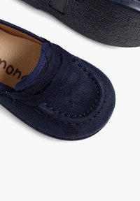 Marineblaues Veloursleder Slipper mit runder Zehenpartie, dekorativer Naht und glatter Textur. Weiche Innensohle mit beiger Innenausstattung.