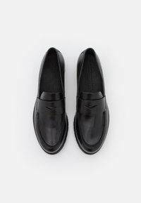 Melni ādas loafers ar gludu virsmu, piedāvājot platu joslu pāri kājai un smalku šuvju detaļu gar malām.