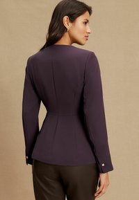 Blazer prins pe purpurie, cu mâneci lungi, stil peplum, din material fin, cu accente de nasturi pe mansete, văzut din spate.