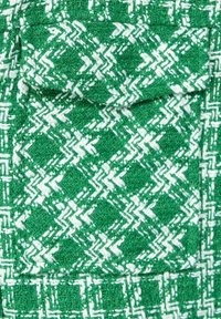 Grön och vit texturerad tyg med ett hundtandsmönster, med en fickdetalj och vävd design, som visar en rik, taktil utseende.