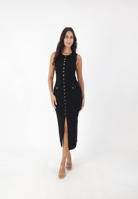 Schwarzes, geripptes Midikleid mit einer Frontknopfverschluss, leichtem Seitenschlitz und zwei Klappentaschen mit goldenen Akzenten. Glatte Textur.