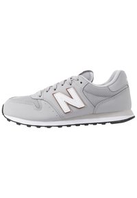 Grauer Sportschuh mit Mesh- und synthetischen Overlays, ausgestattet mit einem weißen und roségoldenen "N"-Logo, strukturiertem Sohlenprofil und klassischem Schnürdesign.