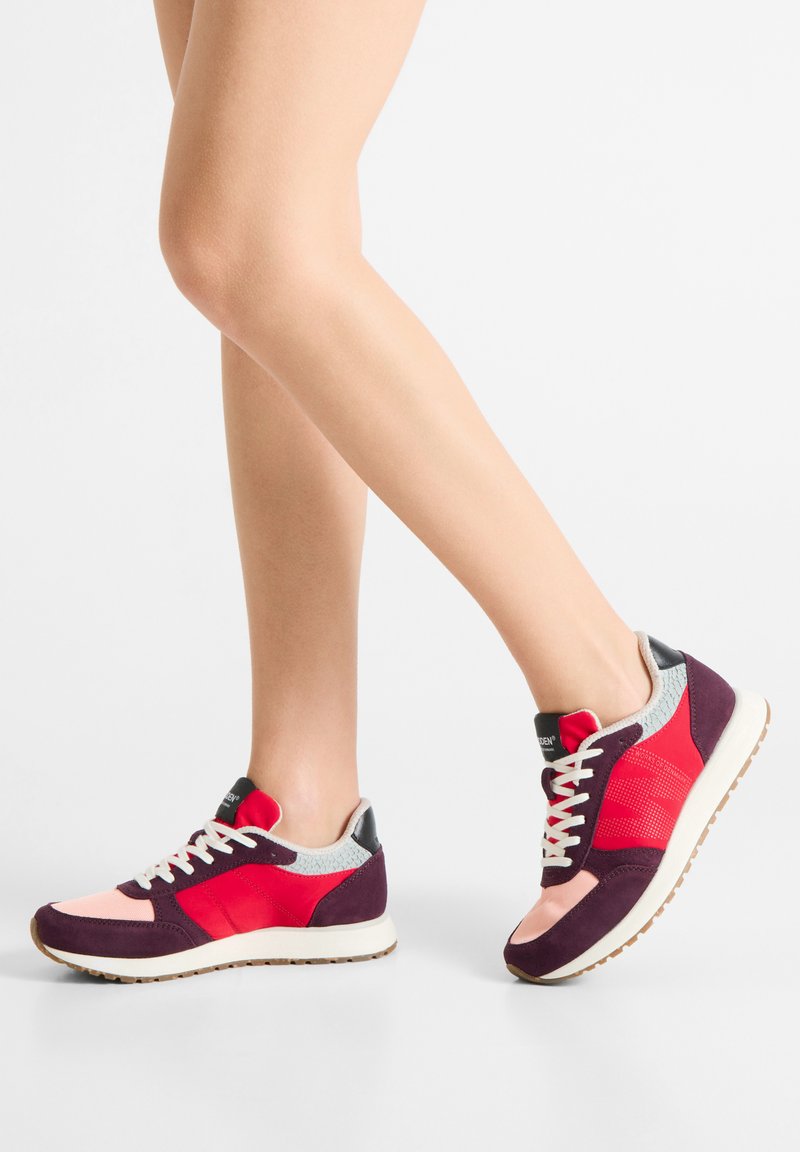 Colorful sneakers featuring a mix of red, pink, and purple materials, with a textured gray collar and white laces on a light sole.