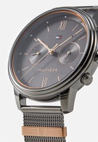 Reloj de hombre con un dial gris oscuro, acentos en oro rosa, una correa de malla y tres sub-diales. Marcas para las horas y la marca visibles.
